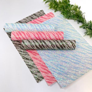 May include: Four sheets of iridescent glitter fabric with a zebra print pattern. The sheets are in shades of pink, blue, and black.