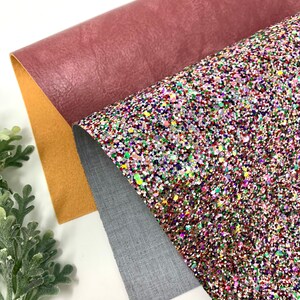 May include: Three sheets of fabric, one is a deep pink faux leather, one is a light gray textured fabric, and the last is a multi-colored glitter fabric.