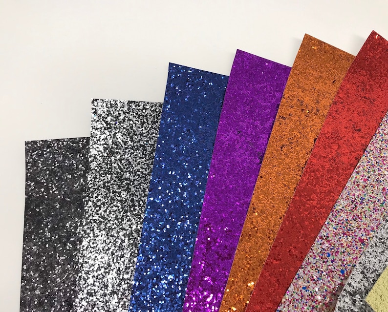 May include: Assortment of glitter paper sheets in various colors, including black, silver, blue, purple, orange, and multi-colored.