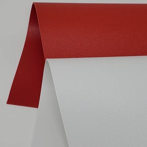 May include: Two sheets of textured vinyl, one red and one white. The sheets are folded in half and are lying on a white surface.