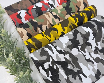 May include: A stack of six different camouflage patterned faux leather sheets. The sheets are arranged in a fan shape, with the bottom sheet being a gray and black camouflage pattern, the next sheet being a yellow and black camouflage pattern, the next sheet being a green and brown camouflage pattern, the next sheet being a red and black camouflage pattern, the next sheet being a brown and black camouflage pattern, and the top sheet being a brown and black camouflage pattern.