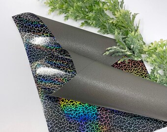 May include: A sheet of black faux leather with a cracked, iridescent finish. The leather is folded over to reveal a solid gray faux leather underneath.