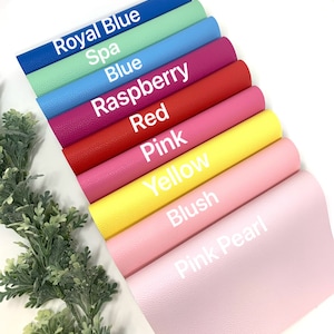 Puede incluir: Una pila de ocho hojas de cuero sint&eacute;tico de diferentes colores. Los colores son azul real, spa, azul, frambuesa, rojo, rosa, amarillo, rubor y rosa perla.
