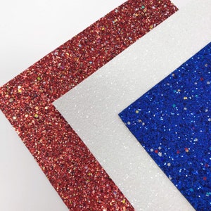 May include: Three sheets of glitter paper in red, white, and blue. The sheets are arranged in a triangle shape.