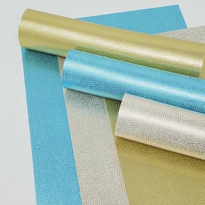 May include: Four rolls of textured, metallic vinyl in gold, silver, and blue. The vinyl has a subtle, embossed pattern.