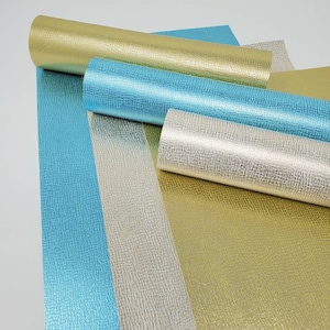 May include: Four rolls of metallic textured paper in gold, silver, and blue. The paper has a subtle embossed pattern.