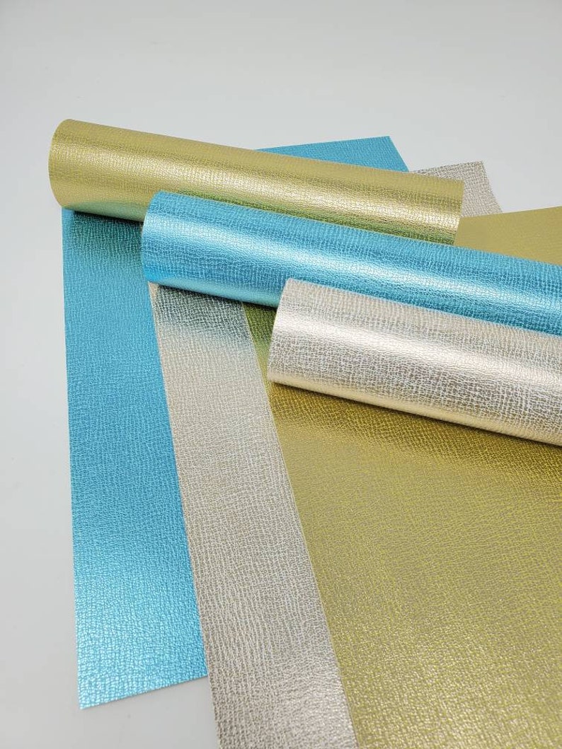 May include: Four rolls of metallic textured paper in gold, silver, and blue. The paper has a subtle embossed pattern.