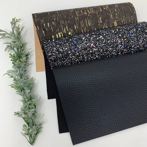 May include: Four sheets of fabric in different textures and colors. The top sheet is a brown cork fabric with gold flecks. The second sheet is a black fabric with a sparkly finish. The third sheet is a black faux leather fabric. The bottom sheet is a black fabric.