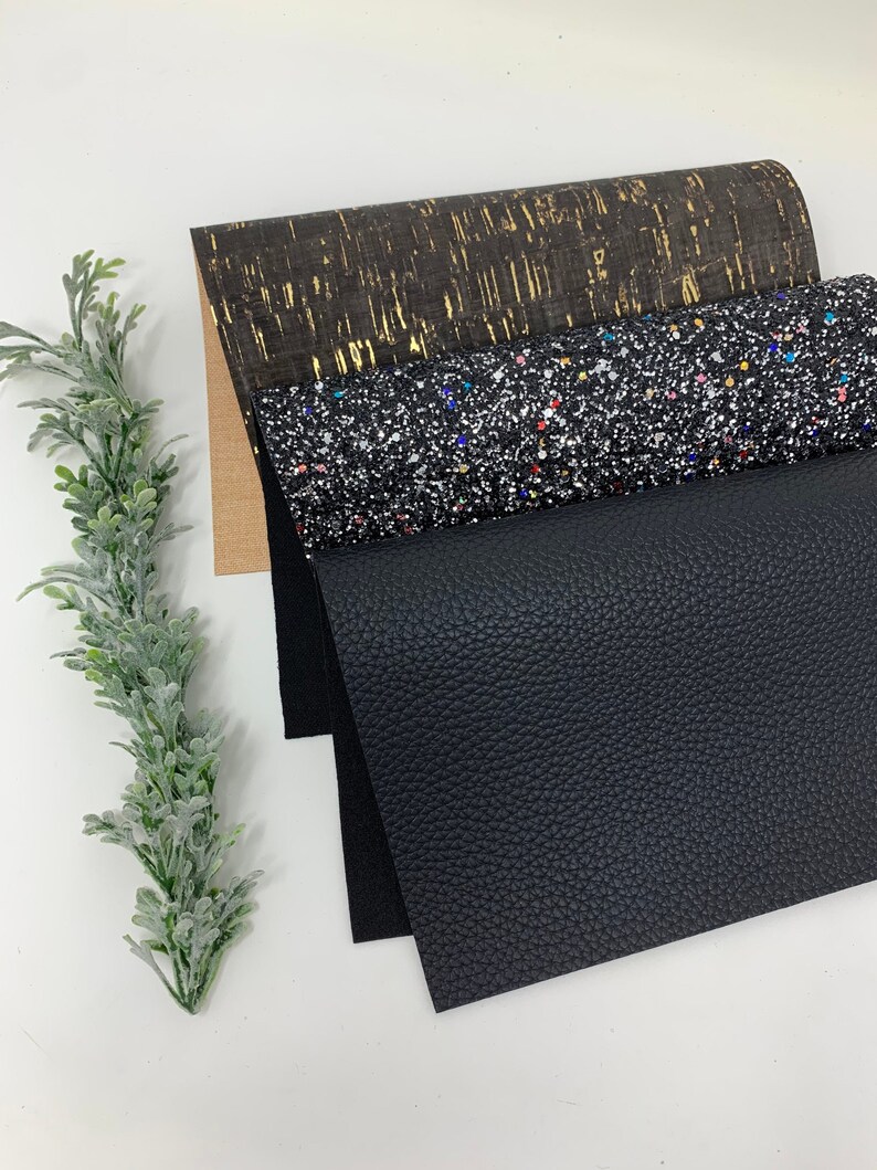 May include: Four sheets of fabric in different textures and colors. The top sheet is a brown cork fabric with gold flecks. The second sheet is a black fabric with a sparkly finish. The third sheet is a black faux leather fabric. The bottom sheet is a black fabric.