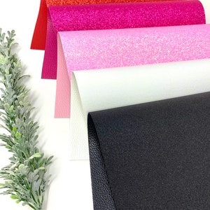 May include: Four sheets of faux leather in different colors and textures. The sheets are stacked on top of each other. The top sheet is red with a glitter finish. The second sheet is pink with a glitter finish. The third sheet is white with a subtle glitter finish. The bottom sheet is black with a textured finish.