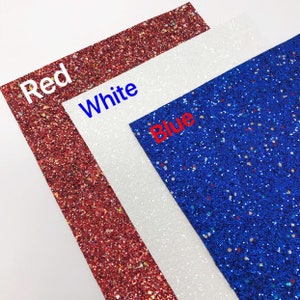 May include: Three sheets of glitter paper in red, white, and blue. The sheets are stacked on top of each other, with the red sheet on the bottom, the white sheet in the middle, and the blue sheet on top.