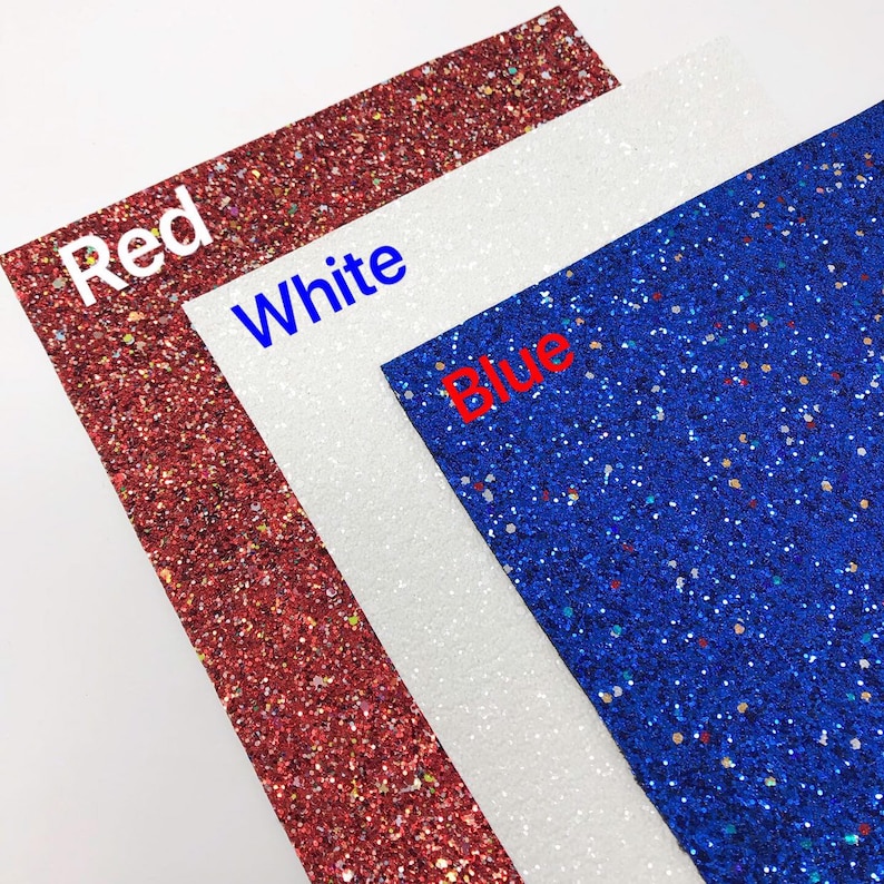 May include: Three sheets of glitter paper in red, white, and blue. The sheets are stacked on top of each other, with the red sheet on the bottom, the white sheet in the middle, and the blue sheet on top.