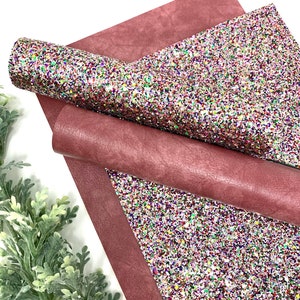 May include: A sheet of burgundy faux leather with a sheet of multi-colored glitter fabric on top. The glitter fabric has a white base with red, green, blue, and purple glitter.