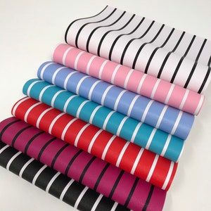 May include: A stack of six striped fabric sheets in various colors, including black, white, pink, blue, red, and purple. The stripes are all horizontal and the fabric has a textured surface.