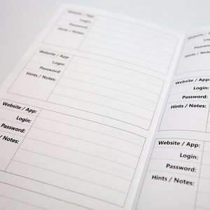 May include: Open notebook with multiple pages featuring sections labeled "Website / App", "Login", "Password", and "Hints / Notes". The pages are white with black text and lines, designed for organizing online account information.