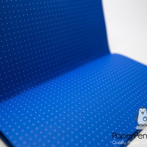 May include: Open notebook with a vibrant blue cover featuring a pattern of small white dots. The notebook is open, revealing the interior pages. The Paper Penguin Co. logo is visible in the bottom right corner.