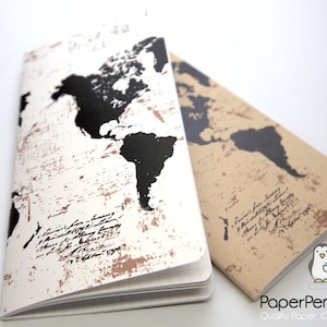 May include: Two notebooks with world map designs. One notebook has a white cover with a distressed brown and black world map. The other notebook has a tan cover with a black world map. Both have script text.