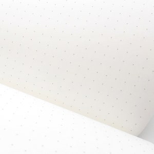 Puede incluir: Primer plano de una hoja de papel blanquecino con un patr&oacute;n de peque&ntilde;os puntos grises espaciados uniformemente. El papel est&aacute; ligeramente curvado, revelando su grosor y textura. Los puntos son de tama&ntilde;o y color consistentes.