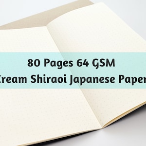 May include: Open notebook with cream-colored pages and dot grid. The text overlay reads "80 Pages 64 GSM Cream Shiraoi Japanese Paper". The notebook is open to reveal the interior pages.
