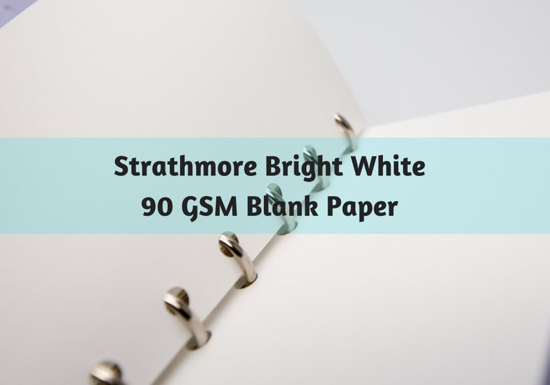 May include: Open notebook with bright white blank paper. The text "Strathmore Bright White 90 GSM Blank Paper" is displayed on a light blue background. The notebook has silver metal rings.