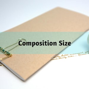 May include: A notebook with a gold binder clip and the text "Composition Size". A roll of decorative tape with gold script is next to the notebook. The notebook has a light brown and green cover.