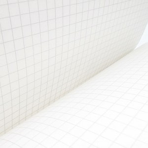 Puede incluir: Primer plano de un cuaderno con papel cuadriculado blanco. Las p&aacute;ginas est&aacute;n ligeramente curvadas, revelando el patr&oacute;n de la cuadr&iacute;cula. El papel es de un blanco brillante y las l&iacute;neas de la cuadr&iacute;cula son de color gris claro.