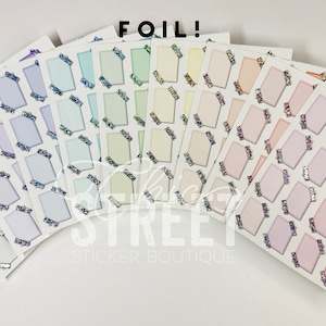 May include: A set of eight sheets of rectangular stickers with a variety of pastel colors and silver glitter accents. The stickers are arranged in a fan shape and have the text "FOIL!" and "CHIC STREET STICKER BOUTIQUE" printed on them.