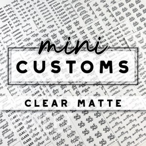 May include: A close-up of a variety of clear matte mini custom stickers with black lettering. The stickers feature a variety of phrases, including "Class", "Family Time", "Eat Out", "Day Off", "To Do", "Laundry", "Late", "Take Out", "Time", "Bills", "Workout", and "Swimming".