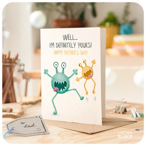 May include: A greeting card with a green and yellow monster illustration. The card reads "WELL... I'M DEFINITELY YOURS! HAPPY FATHER'S DAY!"