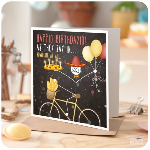 May include: A birthday card with a stick figure wearing a sombrero and riding a bicycle. The stick figure is holding a pizza with candles and balloons. The card says "Happio Birthdayio! As they say in... Nowhere at all."