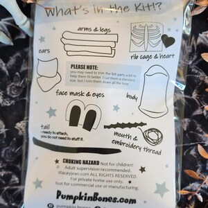 May include: A clear plastic bag containing a craft kit instruction sheet titled What's in the Kit!? with black line drawings of felt parts including arms, legs, a rib cage, heart, ears, face mask, eyes, body, tail, mouth, and embroidery thread.