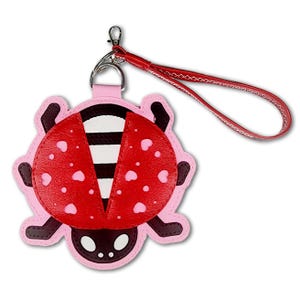 May include: A ladybug-shaped keychain featuring a red wing design with small pink heart cutouts, a white and black striped body, and a dark brown head. The keychain includes a silver metal lobster clasp and a red wrist strap with white stitching.