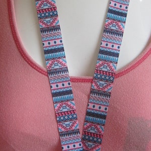 Op de afbeelding: Een roze shirt met een kleurrijk, gepatroneerd koord met een zilveren clip.