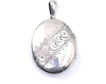 Engraved vintage locket, large oval silver locket with floral and leaf engraving diagonally across the locket.