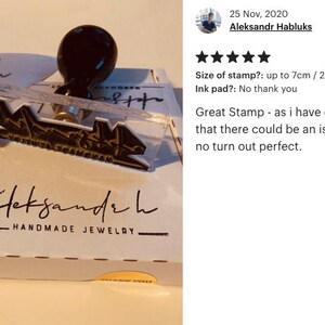 May include: A clear acrylic stamp with a black handle and the text "aleksandr h HANDMADE JEWELRY" in black. The stamp is on a white box with a white ribbon.