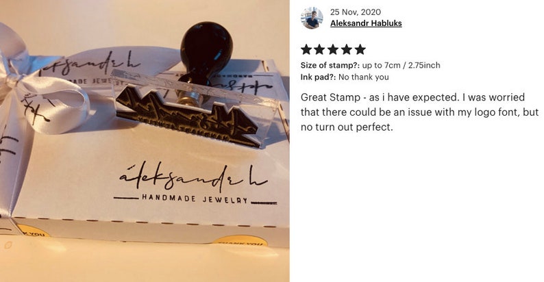 May include: A clear acrylic stamp with a black handle and the text "aleksandr h HANDMADE JEWELRY" in black. The stamp is on a white box with a white ribbon.