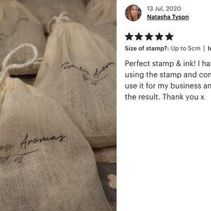 May include: Close-up of several small white muslin bags with the text "Timeless Aromas" printed on them. The bags are arranged on a textured surface. The text "Timeless Aromas" is repeated on each bag.