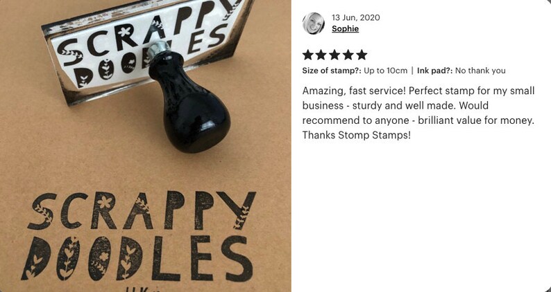 May include: A black rubber stamp with the text "SCRAPPY DOODLES" in white lettering. The stamp is on a brown surface and has a black handle. The text "SCRAPPY DOODLES" is also stamped in black ink on the brown surface.