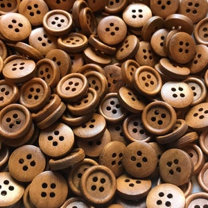 May include: A large pile of brown wooden buttons with four holes each. The buttons are all the same size and shape.