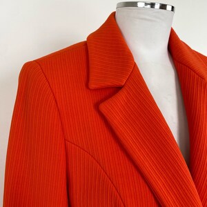 May include: A bright orange blazer with a ribbed texture and a classic notched collar.