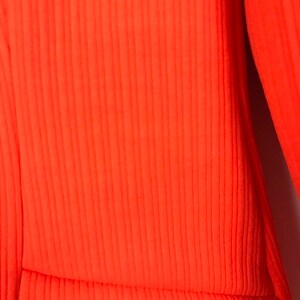 May include: Close-up of a bright orange ribbed fabric. The fabric has a smooth texture and a subtle sheen.