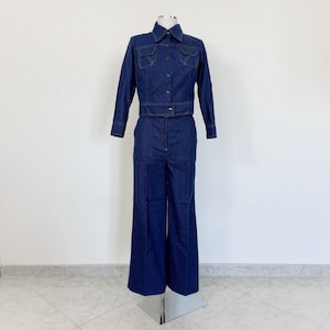 Könnte beinhalten: Ein Jeans-Overall mit einem Kragen-Jackett und weiten Hosenbeinen. Der Overall ist dunkelblau.