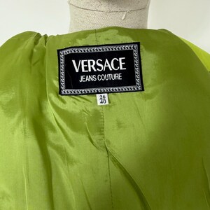 May include: Close-up of a lime green garment's interior. A black and white label reads "VERSACE JEANS COUTURE". Below the label are the numbers "26" and "40".