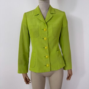 May include: A lime green blazer with a notched collar, long sleeves, and four yellow buttons. The blazer has two front pockets and a tailored fit. The fabric has a subtle texture.