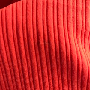 May include: Close-up of a bright orange ribbed fabric. The fabric has a soft, textured surface.