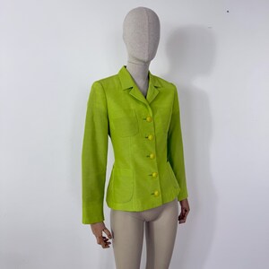 May include: A lime green blazer with a tailored fit, featuring a notched collar, two front pockets, and matching yellow buttons. The jacket is displayed on a mannequin, showcasing its structured design and vibrant color.
