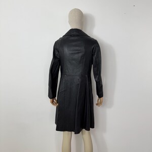 May include: A black leather coat with a classic design. The coat features a notched collar, long sleeves, and a flared skirt. The coat is displayed on a mannequin against a plain white background.