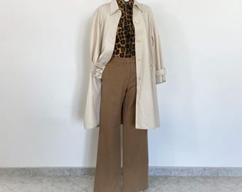 May include: A white trench coat with a brown leopard print shirt and brown wide-leg pants.