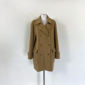 May include: A tan double-breasted coat with a classic design. The coat features a notched collar, two rows of buttons, and two front pockets. The coat is displayed on a mannequin against a white background.