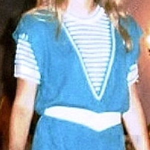 May include: A teal blue jumpsuit with a white striped shirt underneath. The jumpsuit has a white belt and a V-neck.